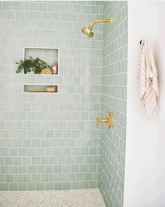 a white tiled shower with gold fixtures and shelves