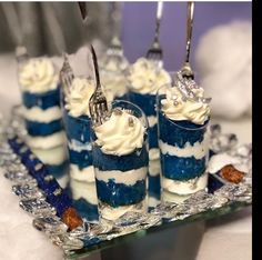 blue and white desserts are arranged on a glass platter with utensils