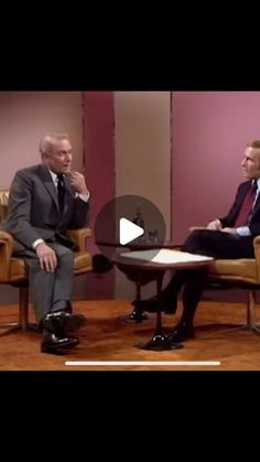 two men sitting in chairs talking to each other on the set of a television show