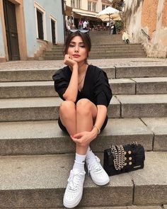 a woman sitting on the steps with her hand under her chin