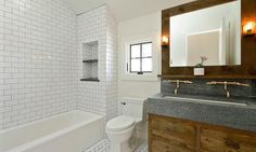 a bathroom with white tile and wood accents on the vanity, toilet and bathtub