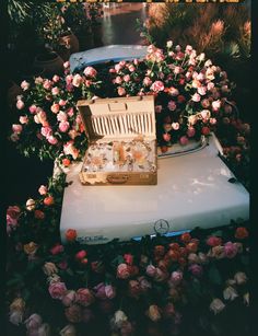 an open suitcase sitting on top of a bed of flowers and roses in the background