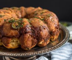 a bundt cake is sitting on a silver platter and has herbs sprinkled all over it