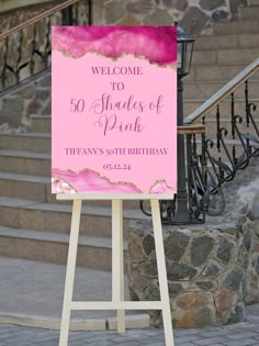 a welcome sign with pink paint on it in front of some stairs and stone steps