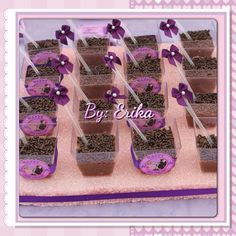 there are many small trays that have chocolate treats on them with purple ribbons and bows