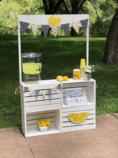 an outdoor lemonade stand is set up in the grass with yellow and white decorations