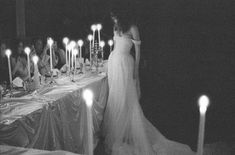 a woman standing in front of a table with candles