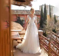 a woman in a wedding dress standing on a balcony