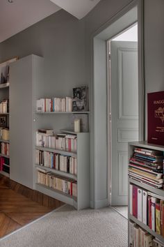 an empty room with bookshelves full of books and a door leading to another room