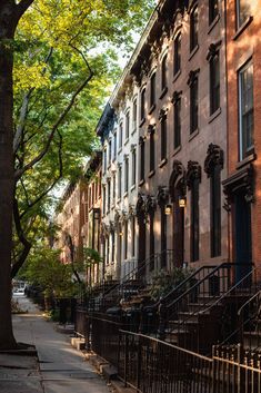 a row of brownstone townhouses on a tree lined street