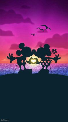 mickey and minnie mouse silhouetted against the sunset