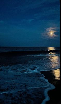 the moon is setting over the ocean with waves