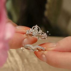 a person holding two rings in their hand with diamonds on them and the middle one has a tiara