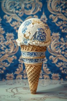 an ice cream cone with blue and white designs on it's top, sitting in front of a wall