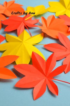 paper leaves are arranged on a blue surface with the words crafts by ann above them