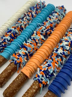 several different colored sticks with sprinkles and blue, orange, and white frosting