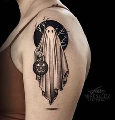 a woman's shoulder with a ghost and pumpkin tattoo on the left side of her arm