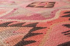 a pink and brown rug with black designs on it