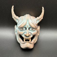 a ceramic mask with horns on it's head sitting on a black counter top