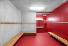 an empty bathroom with red walls and wooden benches