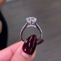 a close up of a person holding a ring with a red nail polish on it