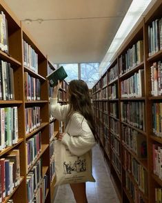 a woman is looking at books in a library with her hand on the book shelf