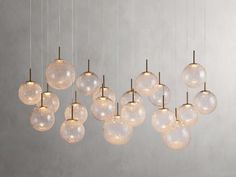 a bunch of glass balls hanging from a ceiling light fixture in a room with concrete walls