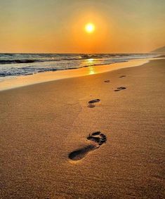 two footprints in the sand near the ocean at sunset