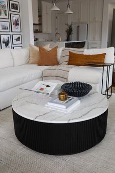 a living room with white couches and a marble coffee table in the center area