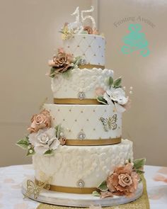 a three tiered wedding cake with flowers and butterflies on the top, sitting on a table