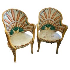 two chairs that are sitting side by side with designs on the back and armrests