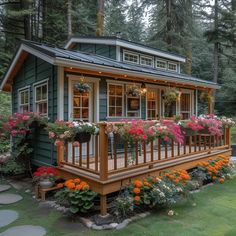 a small green house with flowers on the porch