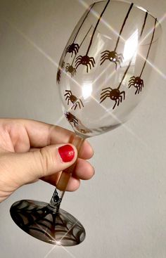 a hand holding a wine glass with spider designs on it