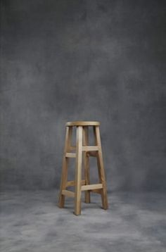 a wooden stool sitting on top of a gray floor