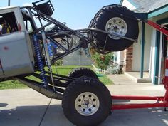 an off - road vehicle is attached to a trailer on the sidewalk in front of a house