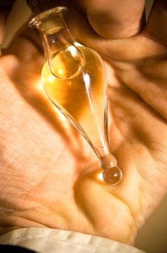 a person holding an empty glass bottle in their hand with the light shining on it