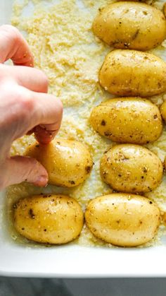 someone is placing potatoes in a casserole dish