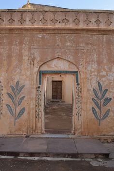 an old building with paintings on the wall and doorway leading to another room in it