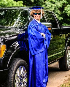 a man in a graduation gown standing next to a truck