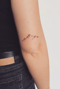 a woman's arm with a small mountain tattoo on the left side of her arm