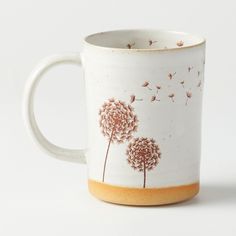 a coffee cup with dandelions painted on the outside and inside, sitting on a white surface