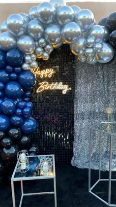 balloons are on display in front of a birthday backdrop and table with an open umbrella