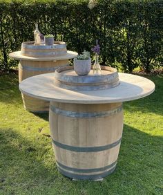 three wine barrels are sitting on the grass near each other, with plants growing out of them