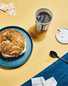 a bagel sitting on top of a blue plate next to a cup of coffee