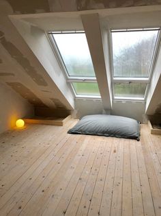 an empty room with two windows and a pillow on the floor