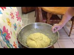 a person mixing dough into a metal bowl