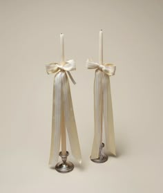 two candles with bows on them sitting next to each other