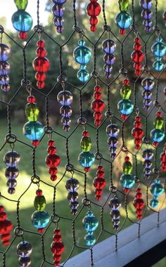 colorful glass beads are hanging on the side of a window