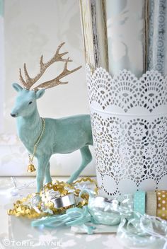 a blue deer figurine sitting next to a white vase with gold decorations on it