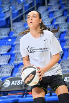 a woman in white shirt and black shorts holding a basketball